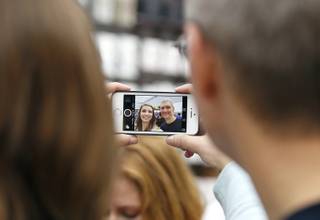 Tim Cook, CEO of Apple Inc., takes a photograph with Apple employee at the Apple Store during the launch and sale of the new iPhone 6 on Friday, Sept 19, 2014 Palo Alto, Calif. 