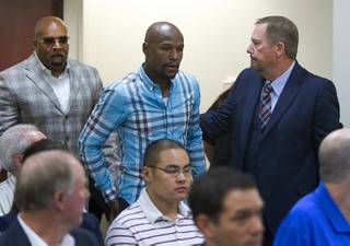 Boxer Floyd Mayweather Jr., center, arrives with Mayweather Promotions CEO Leonard Ellerbe, left, and attorney Shane Emerick during a Nevada State Athletic Commission at the Sawyer State Building Tuesday, Sept. 23, 2014. Commissioners expressed concern about activities at his gym that were broadcast on Showtime's 