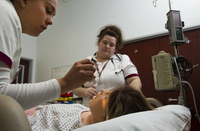 Nursing students Veronica Segura and Theresa Ferri tend to Sim Mom who is experiencing head pain during a patient simulation lab with mannequins in the nursing program at Roseman University on Thursday, September 18, 2014.  L.E. Baskow.