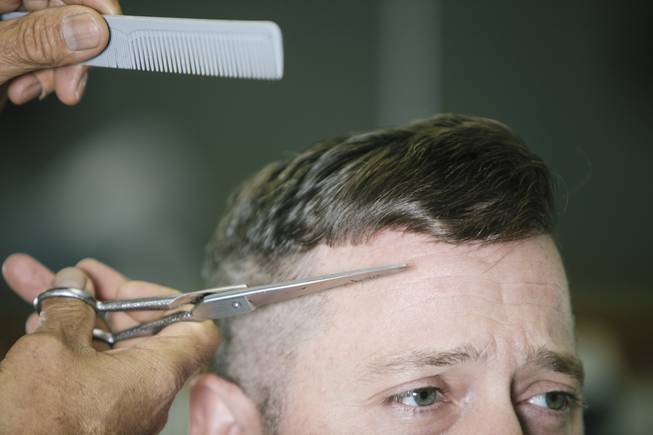 Ernesto Ortiz cuts Chris Kellam's hair at the El Cortez Barbershop in Las Vegas, Nev. on September 20, 2014.