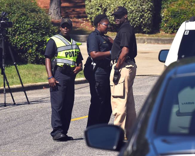 Police officers confer near the scene where three people were killed, including the gunman, at a UPS facility in Birmingham, Ala., Tuesday, Sept. 23, 2014.