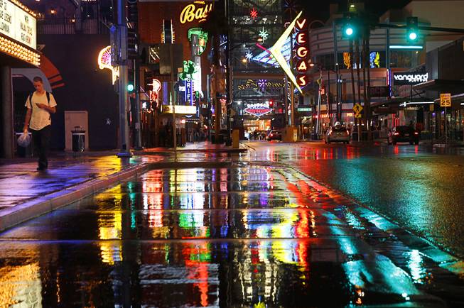 Neon lights reflect on East Fremont Street in downtown Las Vegas after a rainstorm Friday, Sept. 26, 2014.  