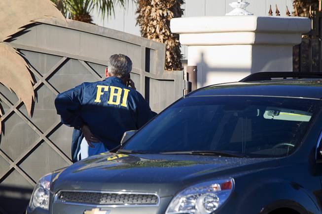 An agent stands by an entrance as the FBI conducts a search warrant at a home on Oquendo Road near Lamb Boulevard on Monday, Sept. 29, 2014.