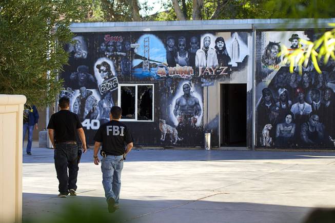 FBI agents walk by a music studio to the rear of a home on Oquendo Road near Lamb Boulevard during an FBI raid Monday Sept. 29, 2014.