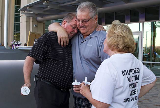 Ron Cornell, left, gets a hug from Les and Sandy Sharp after a ceremony to honor the lives of homicide victims, including those killed by domestic violence, at Metro Police Headquarters Tuesday, Sept. 30, 2014. Cornell's son Joey was killed in 1998. Rory Sharp was killed in 1992.
