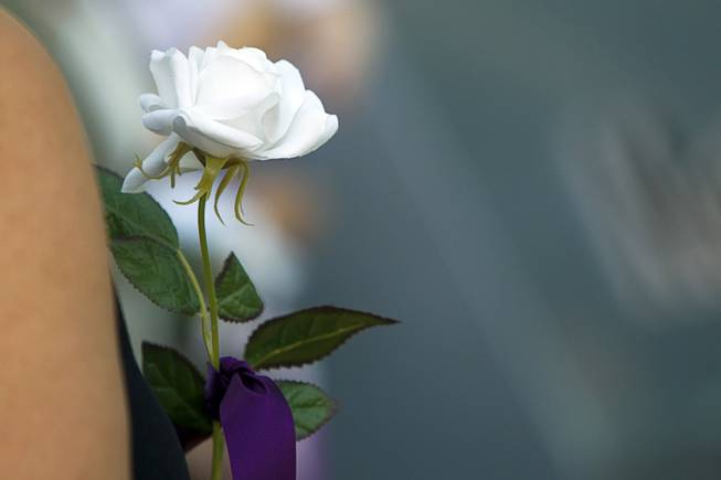 A woman holds a rose during a ceremony to honor the lives of homicide victims, including those killed by domestic violence, at Metro Police Headquarters Tuesday, Sept. 30, 2014.