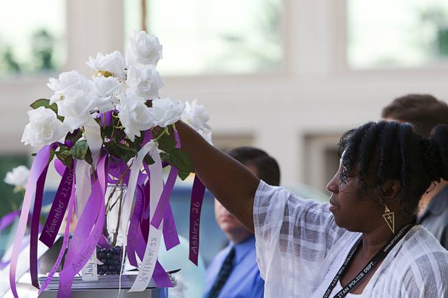 Regina Porter, a victim advocate with Metro's Special Victims Unit, places a rose in a vase during a ceremony to honor the lives of homicide victims, including those killed by domestic violence, at Metro Police Headquarters Tuesday, Sept. 30, 2014.