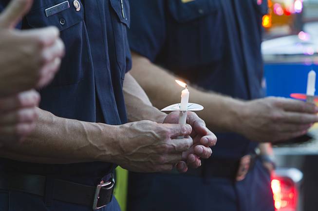 Firefighters hold candles during a ceremony to honor the lives of homicide victims, including those killed by domestic violence, at Metro Police Headquarters Tuesday, Sept. 30, 2014.