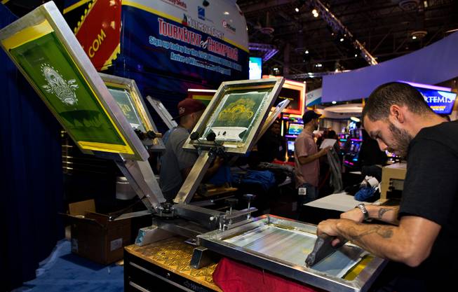 John Herrera of Multimedia Games Inc., silk screens gaming shirts for attendees at the Global Gaming Expo (G2E) within the Sands Expo onTuesday, September 30, 2014.