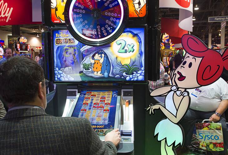 A man tries out a Flintstones slot machine in the WMS Gaming booth during the final day of the Global Gaming Expo (G2E) at the Sands Expo Center Thursday, Oct. 2, 2014.