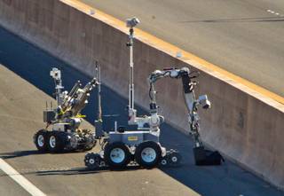 Bomb squad robots investigate a suspicious backpack on the road along the I-15 southbound past Hacienda Ave. on Wednesday, October 2, 2014.