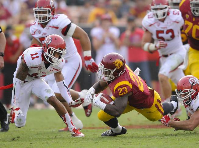 Southern California running back Tre Madden (23) is tripped up as the attempts to get by Utah defensive back Davion Orphey (11) during the second half of an NCAA college football game, Saturday, Oct. 26, 2013, in Los Angeles. USC won 19- 3. (AP Photo/Gus Ruelas)