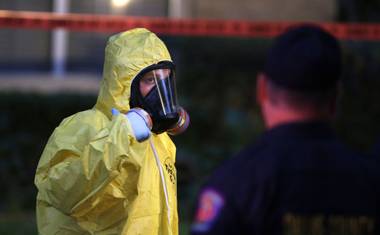 A hazmat worker looks up while finishing up cleaning outside an apartment building of a hospital worker, Sunday, Oct. 12, 2014, in Dallas. The Texas health care worker, who was in full protective gear when they provided hospital care for Ebola patient Thomas Eric Duncan, who later died, has tested positive for the virus and is in stable condition, health officials said Sunday.