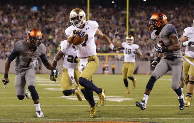 Notre Dame wide receiver William Fuller (7) scores a touchdown as Syracuse cornerback Julian Whigham (1) and safety Durell Eskridge (3) chase him during the first half of an NCAA college football game, Saturday, Sept. 27, 2014, in East Rutherford, N.J. (AP Photo/Julio Cortez)