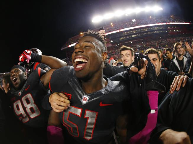 Rutgers' Daryl Stephenson (98) and Sebastian Joseph (51) celebrate as fans flood the field after Rutgers defeated Michigan 26-24 in an NCAA college football game Saturday, Oct. 4, 2014, in Piscataway, N.J.