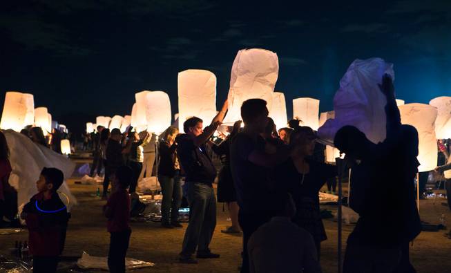 Participants team up to inflate their lanterns before liftoff during the Rise Lantern Festival at Jean Dry Lake Bed on Saturday, Oct. 18, 2014, in Jean.