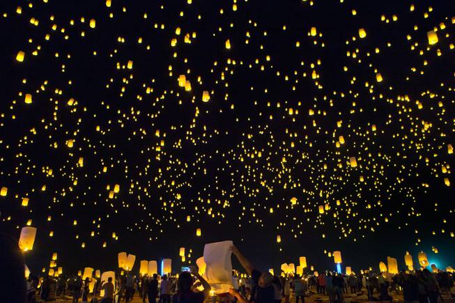 Lanterns float into the night sky as more are inflated for release during the Rise Lantern Festival at Jean Dry Lake Bed on Saturday, Oct. 18, 2014, in Jean.