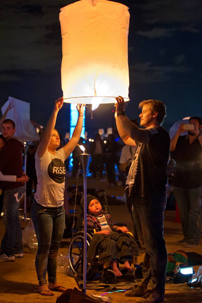 Amber and Antonio Barlow of San Diego inflate a lantern as their son Devan, 5, watches mesmerized during the Rise Lantern Festival at Jean Dry Lake Bed on Saturday, Oct. 18, 2014, in Jean.