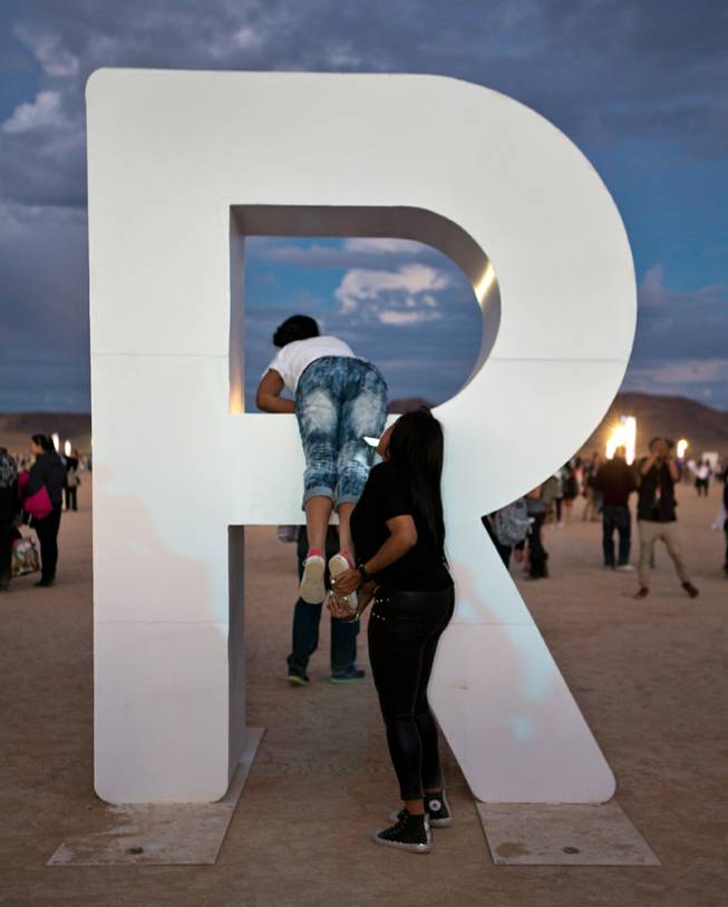 Participants play and pose for pictures on the giant letters at the Rise Lantern Festival at Jean Dry Lake Bed as the sun sets Saturday, Oct. 18, 2014.