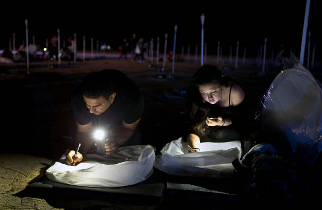 Pat and Mariana Cione of San Diego personalize their lanterns during the Rise Lantern Festival at Jean Dry Lake Bed on Saturday, Oct. 18, 2014, in Jean.