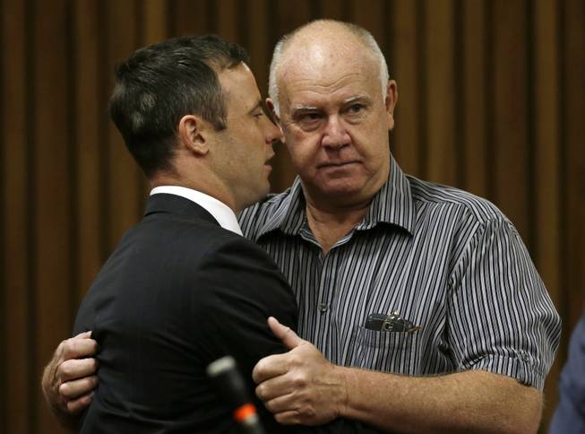 Oscar Pistorius is hugged by his coach Ampie Louw, right, at a court in Pretoria, South Africa, Tuesday, Oct. 21, 2014. Pistorius was sentenced to five years imprisonment by judge Thokozile Masipais for killing his girlfriend Reeva Steenkamp last year.
