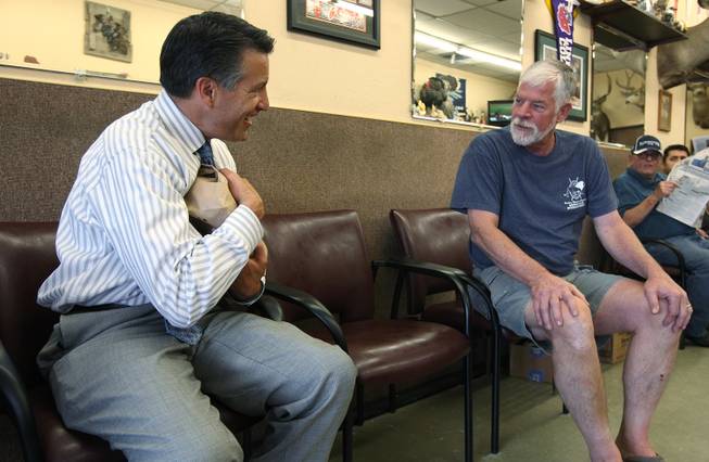 Gov. Brian Sandoval talks with Dan Hawkins while waiting for a haircut, in Sparks, Nev., on Thursday, Oct. 14, 2014. Hawkins, who is hunting partners with Sandoval's barber at the Paradise Park Barber Shop, brought a gift of some fresh game for Sandoval. .Photo by Cathleen Allison
