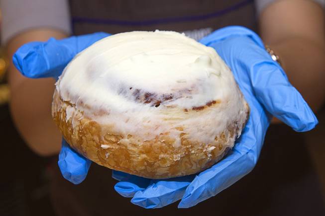 A baker holds a cinnamon roll with cream cheese frosting at Fulton Street Food Hall on Wednesday, Oct. 22, 2014, at Harrah’s.