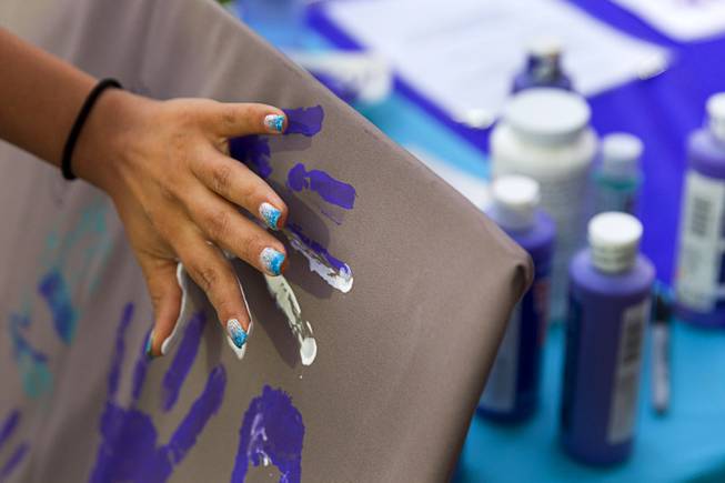 UNLV student Yasmin Tamayo contributes to an art piece during the 21st Annual Take Back the Night rally at UNLV Thursday, Oct. 23, 2014. Participants were encourage to leave the paint on their hands until the end of the event to remind them of the prevalence of violence in the community.