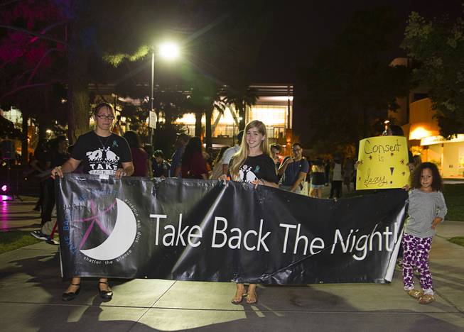 Volunteers Andrea Orwoll, left, Bridgette Walling, center, and Adriana Mancha, 6, hold a banner during the 21st Annual Take Back the Night rally at UNLV Thursday, Oct. 23, 2014.