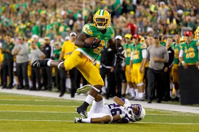 Oregon running back Byron Marshall (9) leaps over Washington defensive back Sidney Jones (26) during the second quarter in an NCAA college football game in Eugene, Ore., Saturday, Oct. 18, 2014. (AP Photo/Ryan Kang)