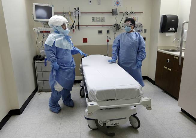 In this Oct. 8, 2014, file photo, Bellevue Hospital nurse Belkys Fortune, left, and Teressa Celia, associate director of Infection Prevention and Control, pose in protective suits in an isolation room, in the Emergency Room of the hospital, during a demonstration of procedures for possible Ebola patients in New York. A doctor who recently returned to New York City from West Africa is being tested for the Ebola virus. 