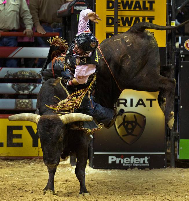 Chase Outlaw leans over sideways working hard to stay atop of Asteroid during the PBR 2014 World Finals on Thursday, October 23, 2014. L.E. Baskow.
