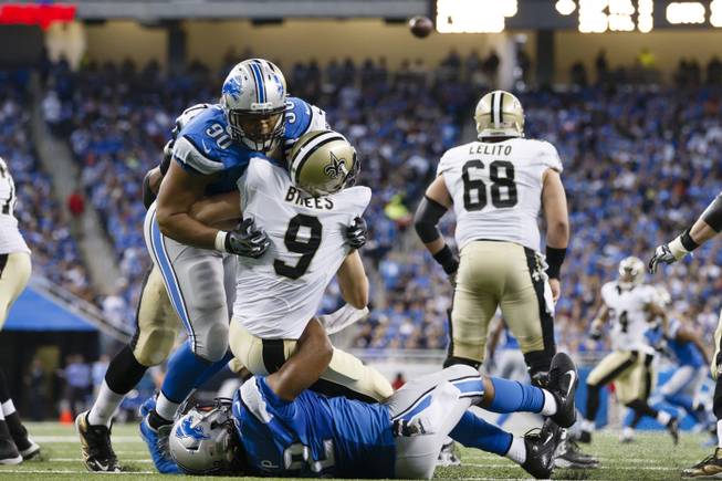 New Orleans Saints quarterback Drew Brees (9) is hit by Detroit Lions defensive tackle Ndamukong Suh (90) and defensive end Darryl Tapp (52) as he passes the ball during an NFL football game at Ford Field in Detroit, Sunday, Oct. 19, 2014.