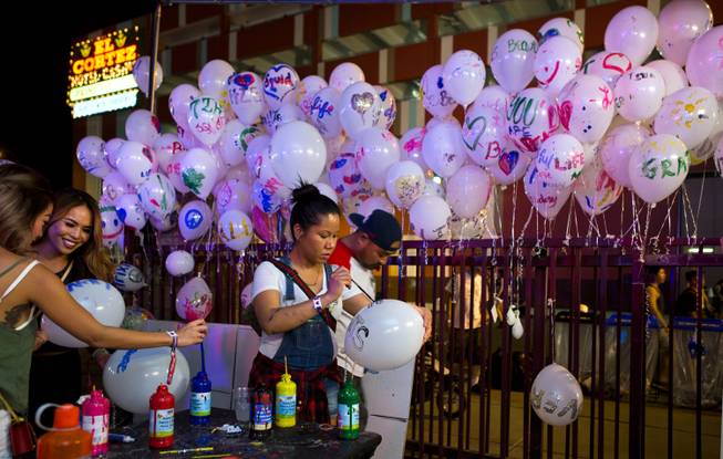 Attendees paint personal messages on balloons to join others during opening day of the Life is Beautiful Festival on Friday, October 24, 2014.