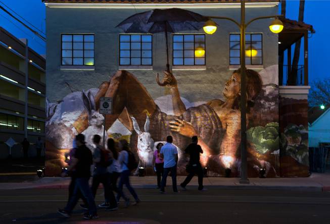 Attendees stream past one of the many interesting painted murals during the opening day of the Life is Beautiful Festival on Friday, October 24, 2014.