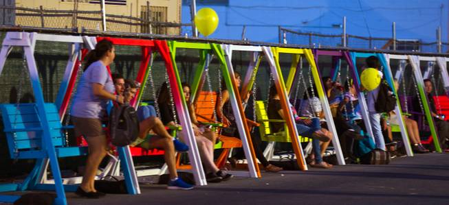 Attendees relax on colorful porch swings during the opening day of the Life is Beautiful Festival on Friday, October 24, 2014.