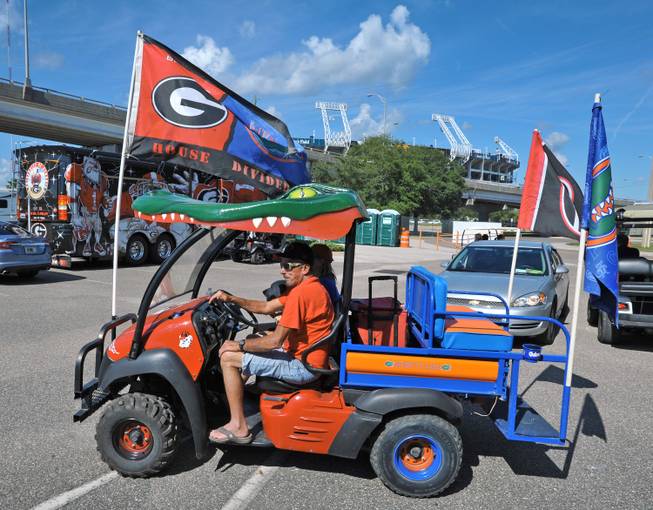 Georgia fan Charles Leverette and his wife Lori Leverette, a Florida fan make their way around RV City Wednesday, Oct. 29, 2014 in their conflicting loyalty painted golf cart as they take in the sites across the street from EverBank Field. The Leverette's arrived in Jacksonville from their home in Gainesville on Saturday and were paying $50 a day to park in a holding lot with no facilities before they could move to RV City Wednesday morning ahead of the weekend's Florida/Georgia game in Jacksonville, Florida.