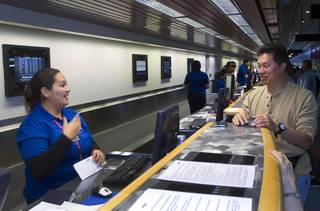 Ticketing agent Joselyn Deleon Guerrero helps Jeff Lee of Canada at the Allegiant Airlines check-in counter in McCarran International Airport Thursday, Oct. 30, 2014. Allegiant is charging a $5 fee for printing boarding passes at the airport. The $5 charge gave a boost to sagging quarterly earnings.