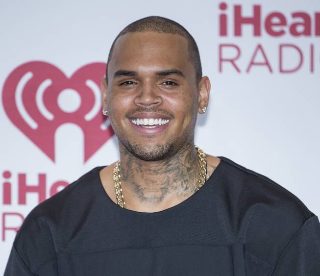 In this Sept. 21, 2014, photo, Chris Brown arrives at the iHeartRadio Music Festival in MGM Grand Las Vegas. The lawyer for a man who was punched by Brown outside a Washington, D.C., hotel says he has settled a lawsuit against the singer. The Washington Post reports that John C. Hayes, the attorney for Parker Adams, confirmed Thursday, Oct. 30, 2014, that a settlement had been reached. 