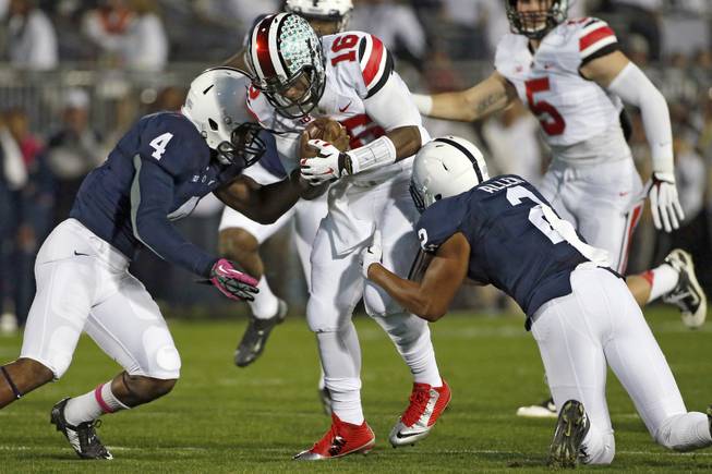 Ohio State quarterback J.T. Barrett (16) runs for a first down before being tackled by Penn State safeties Adrian Amos (4) and Marcus Allen (2) during the first quarter an NCAA college football game in State College, Pa., Saturday, Oct. 25, 2014. (AP Photo/Gene J. Puskar)