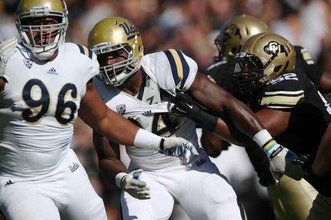 UCLA defensive lineman Owamagbe Odighizuwa, center, is held by Colorado offensive lineman Daniel Munyer, right, as UCLA defensive lineman Eli Ankou follows the play in the second quarter of an NCAA football game in Boulder, Colo., on Saturday, Oct. 25, 2014. (AP Photo/David Zalubowski)