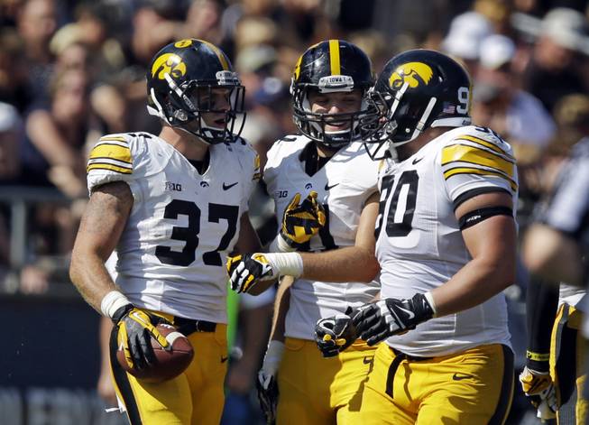 Iowa defensive back John Lowdermilk , left, celebrates an interception against Purdue with teammates Bo Bower, center, and Louis Trinca-Pasat during the second half of an NCAA college football game in West Lafayette, Ind., Saturday, Sept. 27, 2014. Purdue defeated Iowa 24-10. (AP Photo/Michael Conroy)