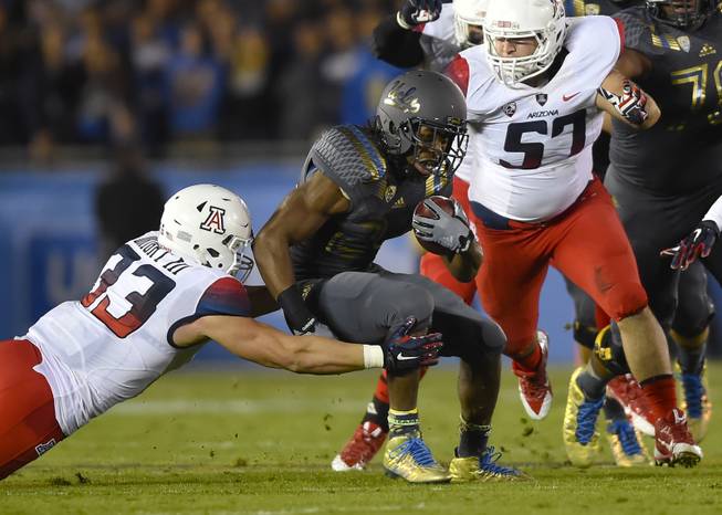 Arizona linebacker Scooby Wright III (33) and linebacker Cody Ippolito (57) close in on UCLA running back Paul Perkins, center, as he rushes during the first half of an NCAA college football game, Saturday, Nov. 1, 2014, in Pasadena, Calif. (AP Photo/Gus Ruelas)