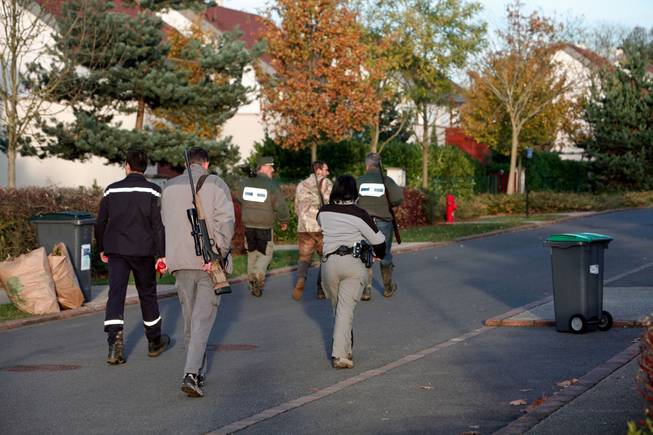 Members of the police animal brigade walk through the streets of Montevrain, east of Paris, France, on Thursday, Nov. 13, 2014. French authorities say a young tiger is on the loose near Disneyland Paris, one of Europe's top tourist destinations, and have urged residents in three towns to stay indoors.