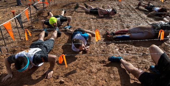 A group of participants slither and roll beneath barbed wire as they navigate through the "Sewage Outlet" during the World's Toughest Mudder about Lake Las Vegas on Saturday, November 15, 2014.
