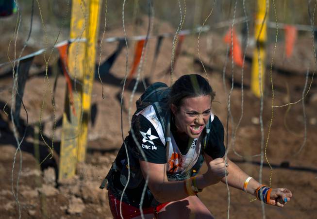 Small electrical shocks tag a participant as she runs through "The Gamble" obstacle during the World's Toughest Mudder about Lake Las Vegas on Saturday, November 15, 2014.