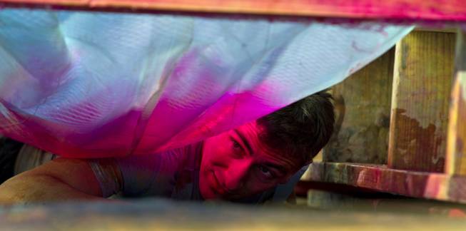 A pink glow illuminates a participant's face as he slithers through the "Birth Canal" obstacle during the World's Toughest Mudder about Lake Las Vegas on Saturday, November 15, 2014.