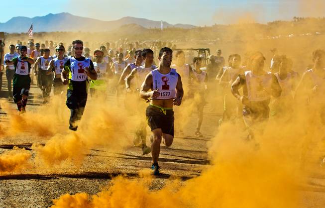 Participants follow a smoke trail as the World's Toughest Mudder 2014 begins about Lake Las Vegas on Saturday, November 15, 2014.