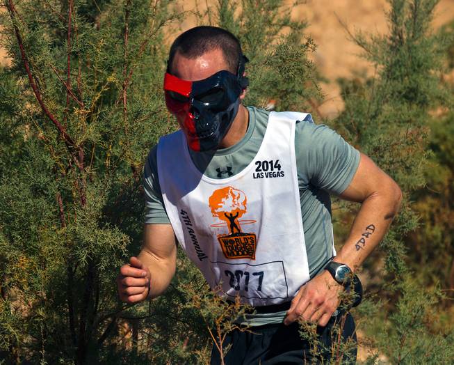 A participant in mask battles through brush along the "Soggy Bottom" obstacle during the World's Toughest Mudder about Lake Las Vegas on Saturday, November 15, 2014.