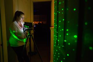 Ghost hunter Jeannine Robertson sets up a camera and light wand in the darkness in the upstairs hallway at the Vaughn's house on Friday, November 16, 2014. The green light is used to detect movement as a figure passes past it.